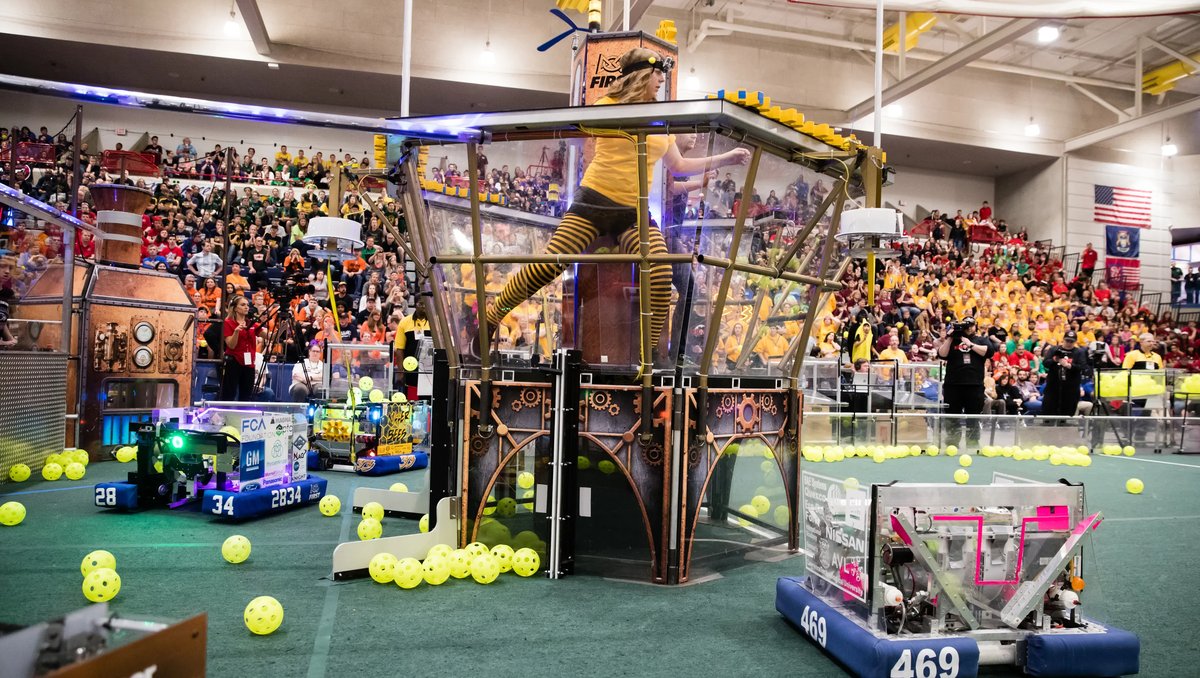 A FIRST robotics competition match in progress, with a themed judging tower and robots on the field